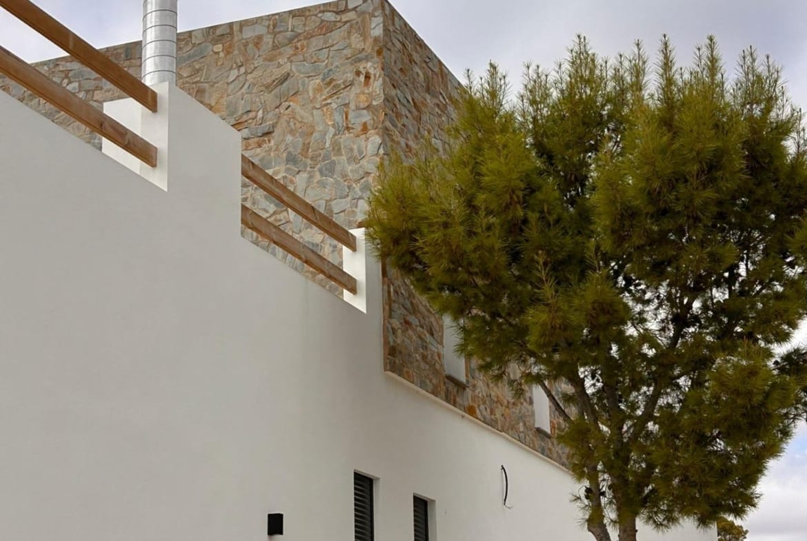 Villa side facade with an upper terrace and stone cladding in Pinoso, Alicante