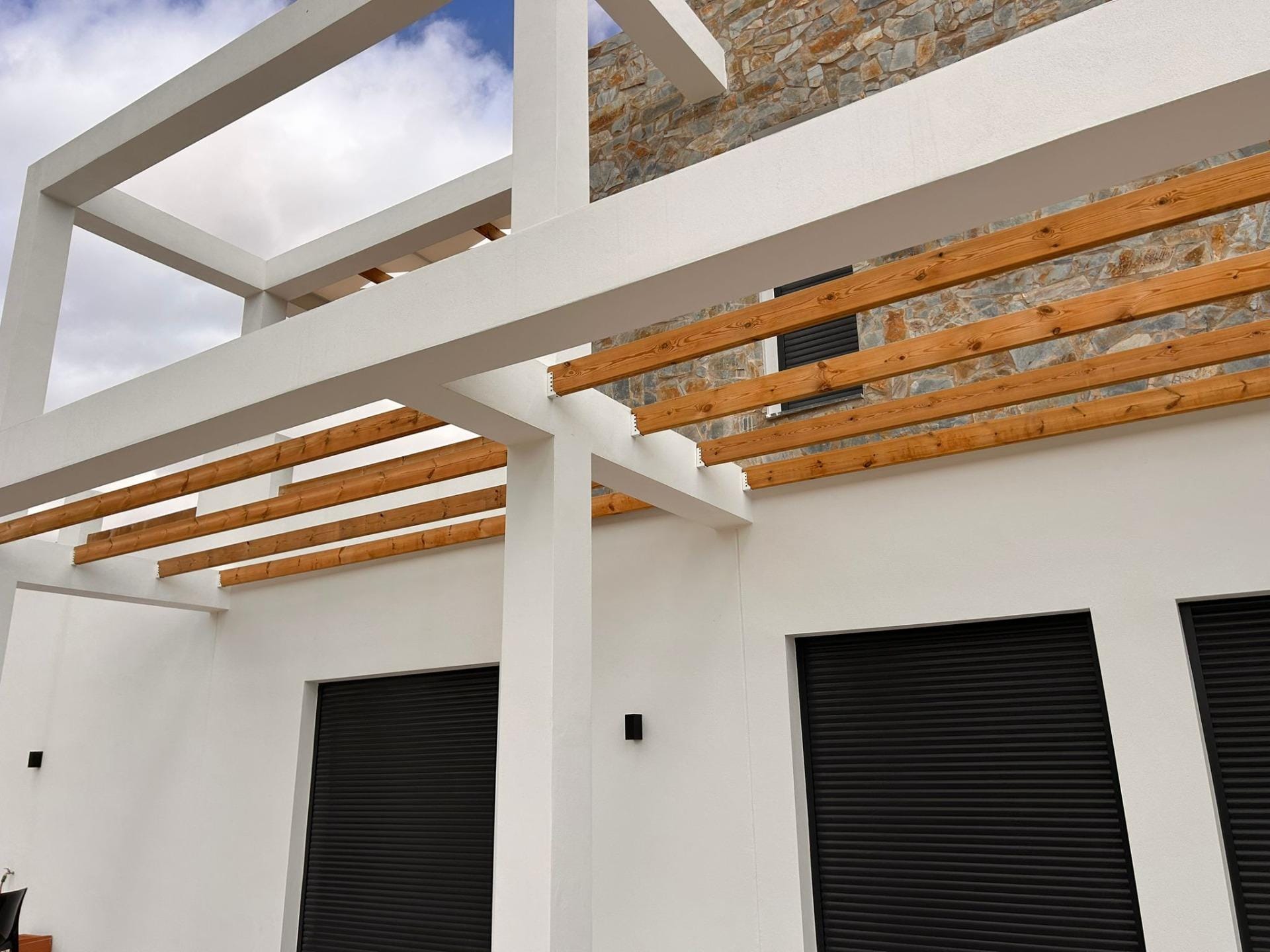 Custom-Built-New-Villas-in-Pinoso-Alicante-Spacious-Homes-in-Natural-Surroundings-34 Terrace beams, wooden railings and stone-clad villa facade in Pinoso, Alicante