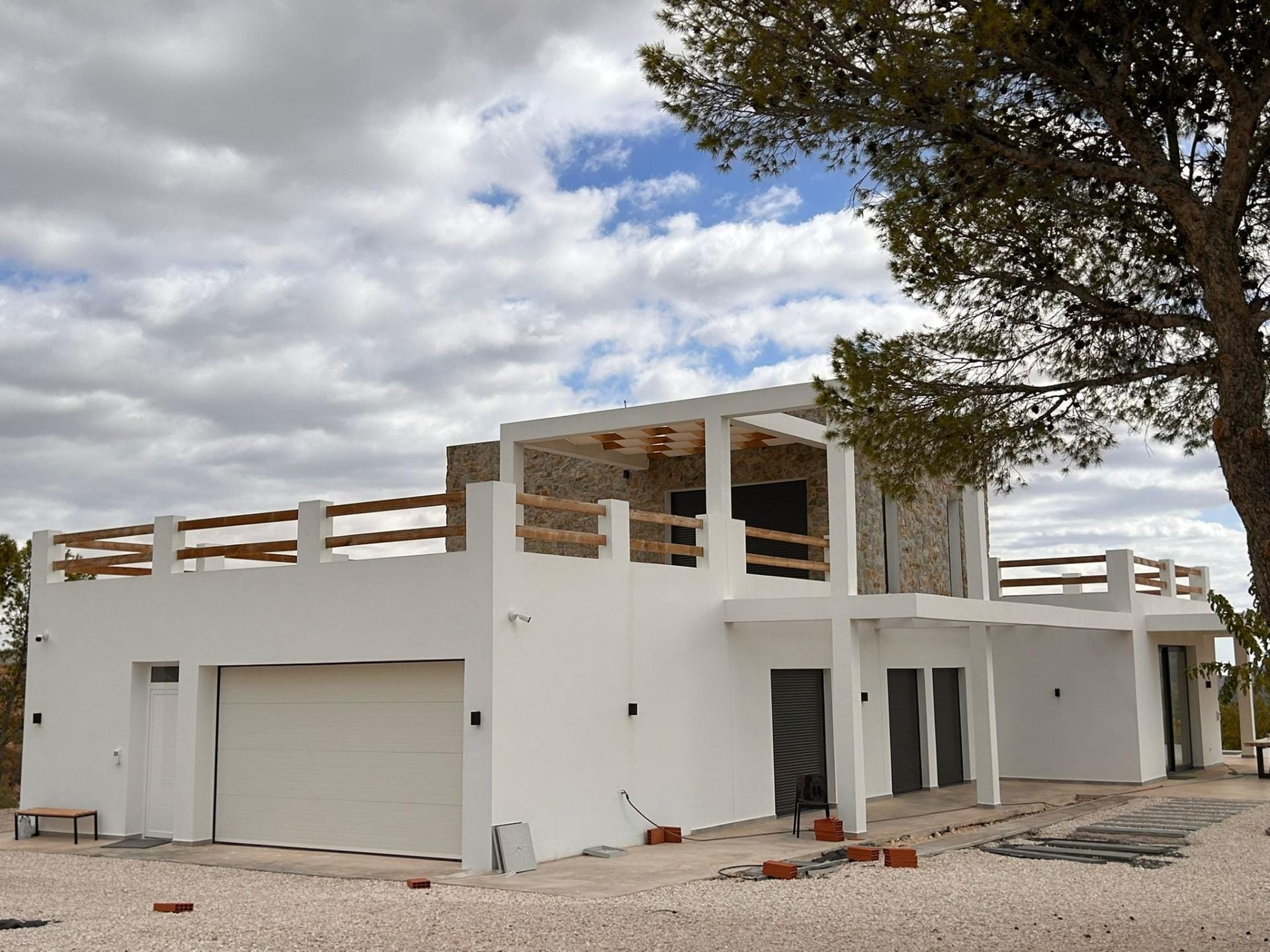 Custom-Built-New-Villas-in-Pinoso-Alicante-Spacious-Homes-in-Natural-Surroundings-4 Villa facade and closed garage beside a gravel forecourt in Pinoso, Alicante