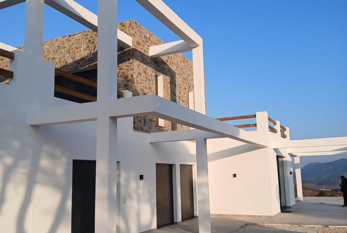 Two-storey villa facade with terrace beams and stone cladding in Pinoso, Alicante