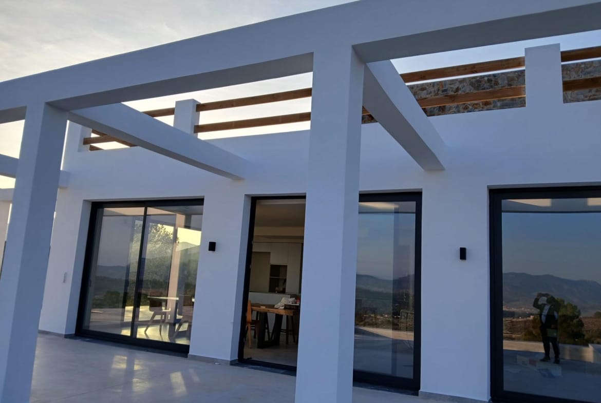 Terrace beams and sliding glass doors on a white villa facade in Pinoso, Alicante