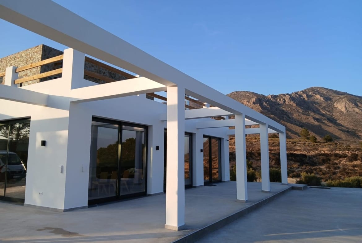 Villa terrace with wide glass doors and a mountain backdrop in Pinoso, Alicante