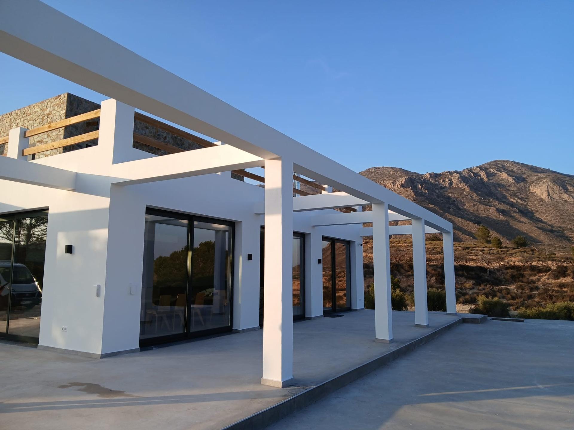 Custom-Built-New-Villas-in-Pinoso-Alicante-Spacious-Homes-in-Natural-Surroundings-6 Villa terrace with wide glass doors and a mountain backdrop in Pinoso, Alicante