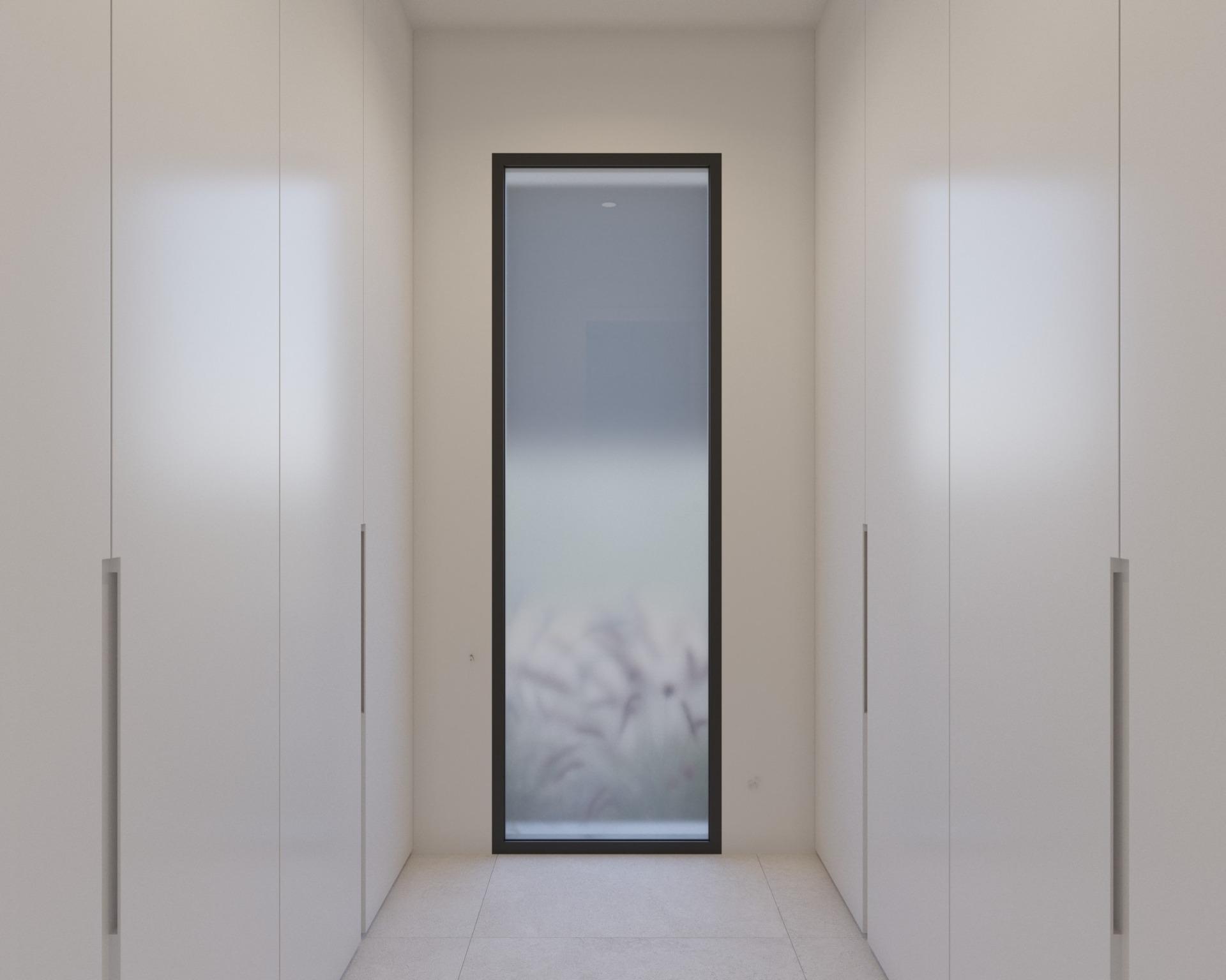 Narrow dressing corridor with floor-to-ceiling wardrobes and tall frosted glass window at end