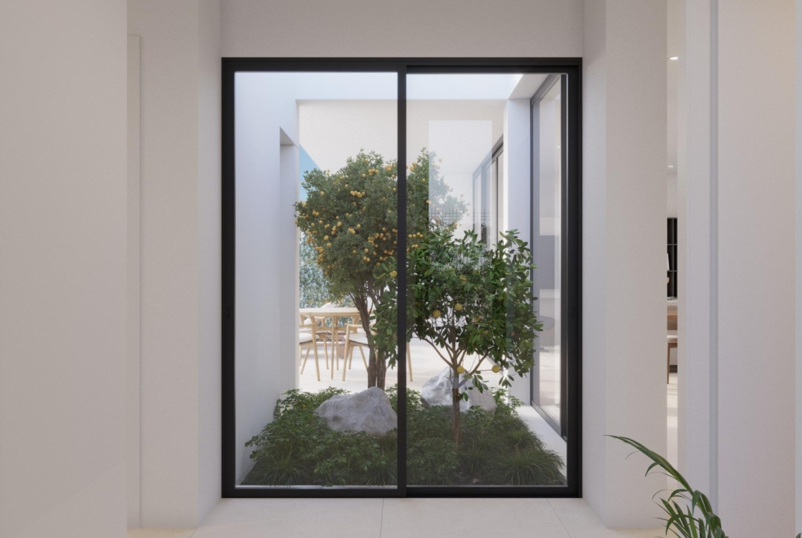 Internal courtyard view through sliding glass doors with small lemon tree and seating