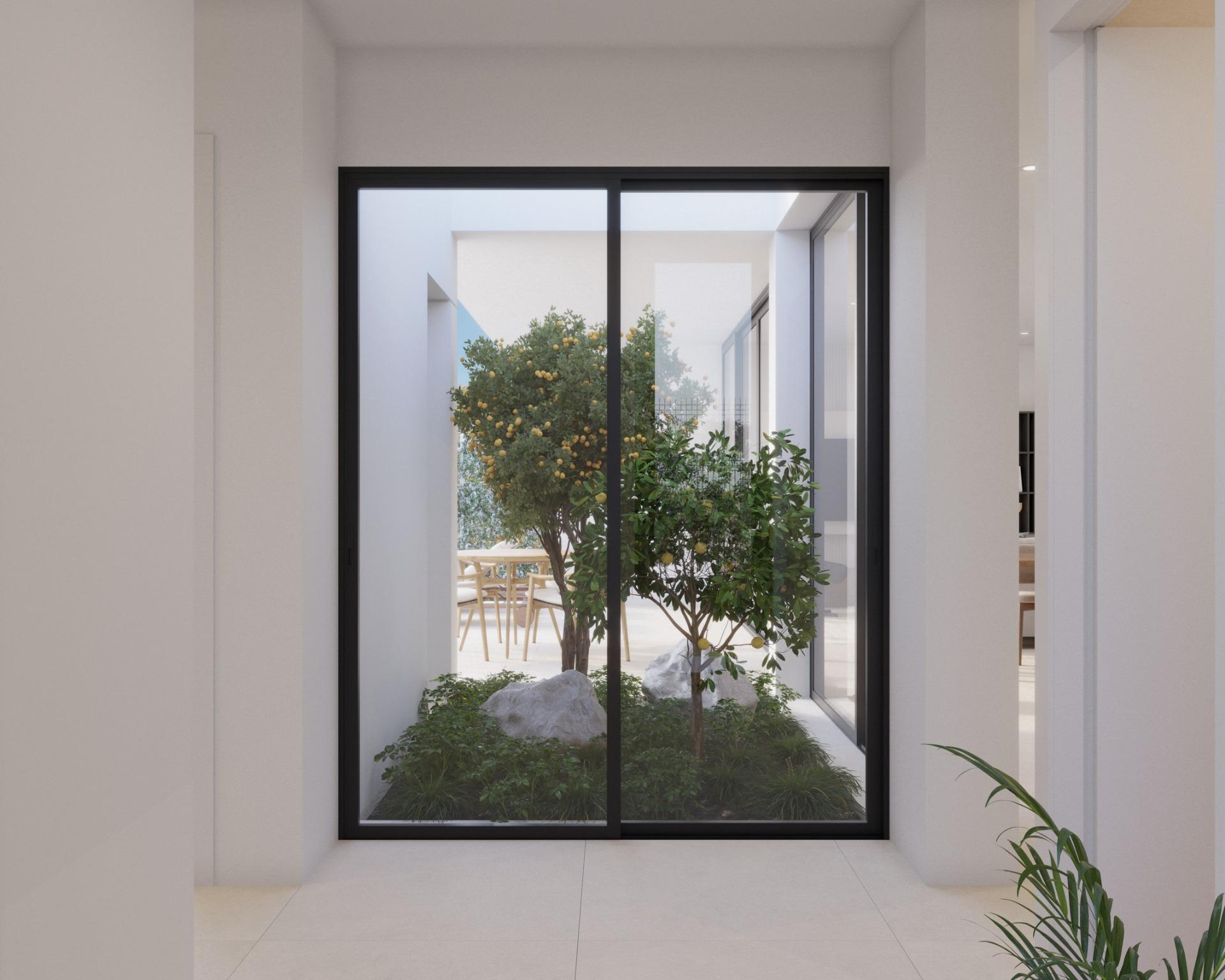 Internal courtyard view through sliding glass doors with small lemon tree and seating