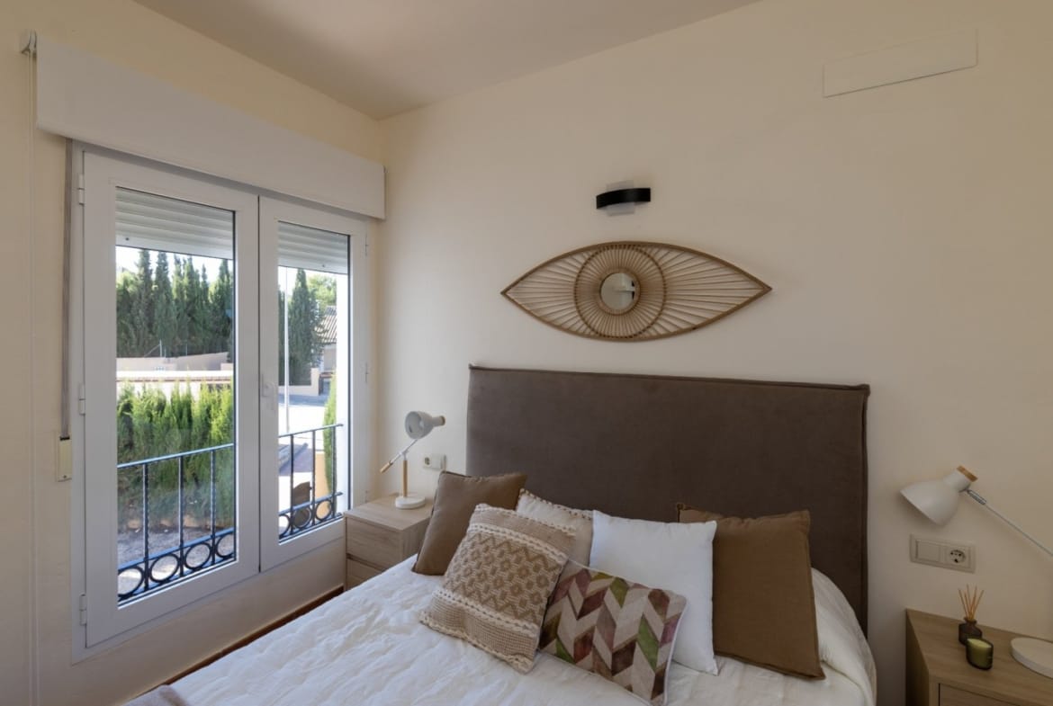 Double bed with a woven wall mirror and bedside table in Las Palas, Fuente Álamo, Murcia