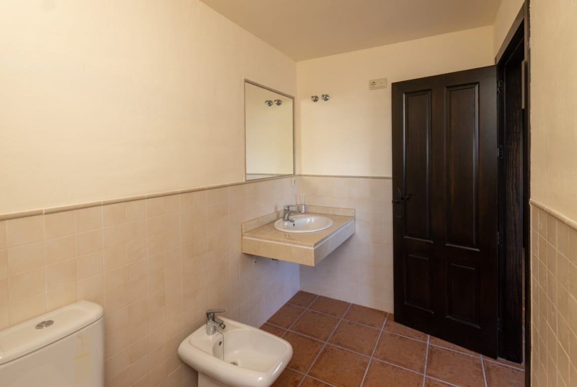 Bathroom with a basin, bidet and dark wooden door in Las Palas, Fuente Álamo, Murcia