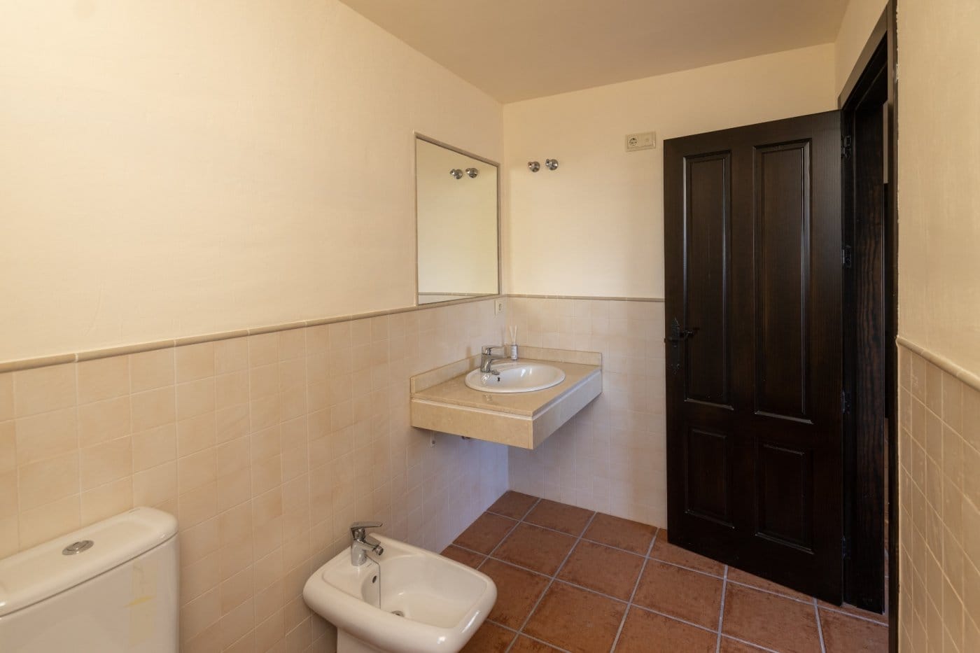 Bathroom with a basin, bidet and dark wooden door in Las Palas, Fuente Álamo, Murcia