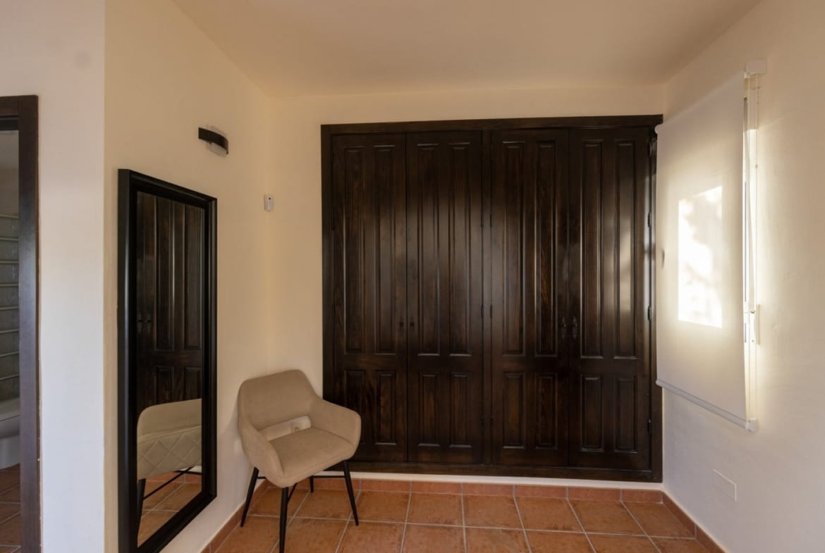 Dark wooden wardrobes beside a chair and full-length mirror in Las Palas, Fuente Álamo, Murcia