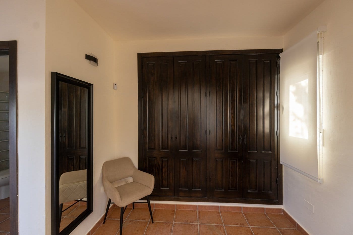 Dark wooden wardrobes beside a chair and full-length mirror in Las Palas, Fuente Álamo, Murcia