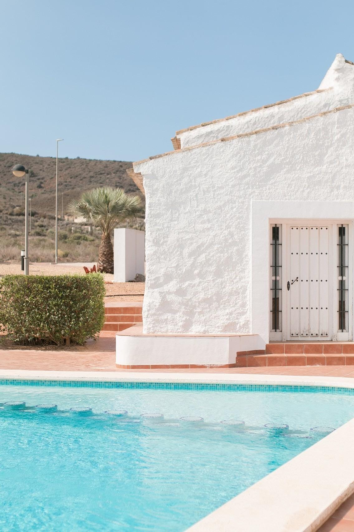 KEY-READY-TOWNHOUSES-IN-FUENTE-ALAMO-MURCIA-2 Pool water beside a white building and hillside backdrop in Las Palas, Fuente Álamo, Murcia