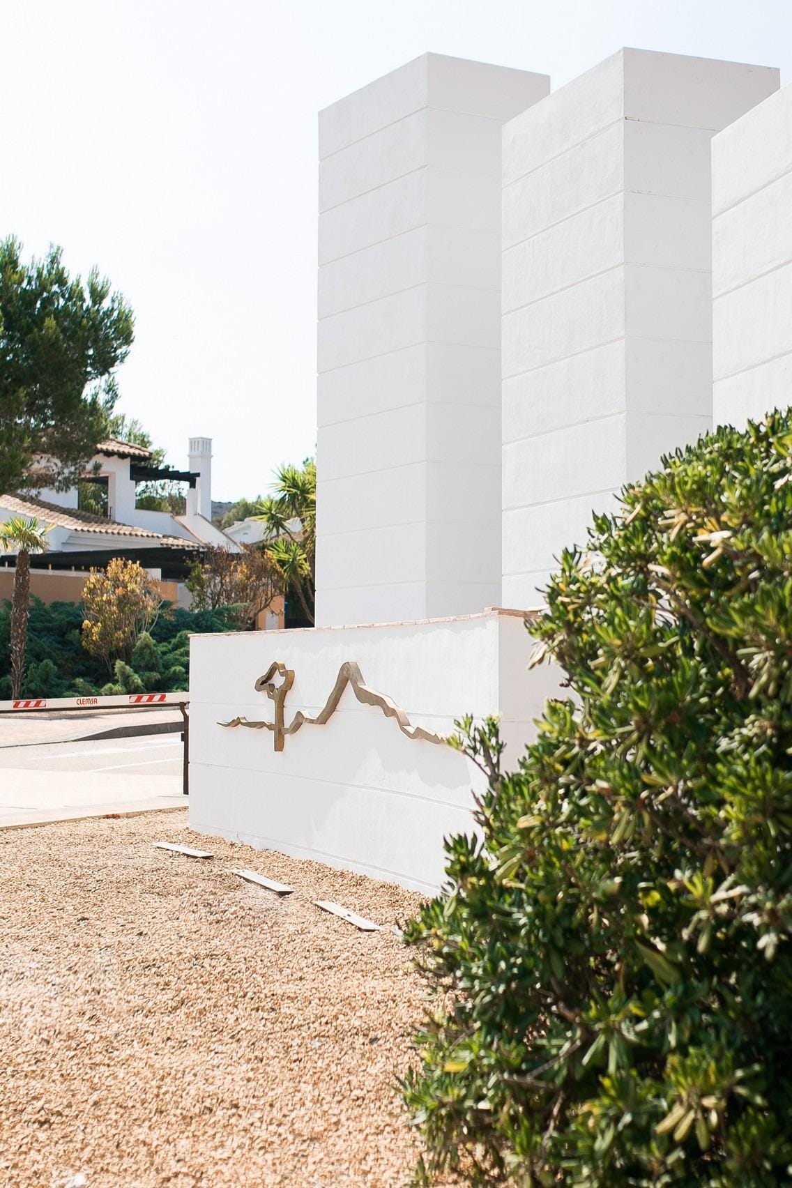 KEY-READY-TOWNHOUSES-IN-FUENTE-ALAMO-MURCIA-9 White entrance towers beside landscaped planting in Las Palas, Fuente Álamo, Murcia