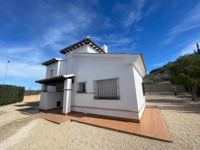 White villa facade with a covered entrance and barred windows in Las Palas, Fuente Álamo, Murcia