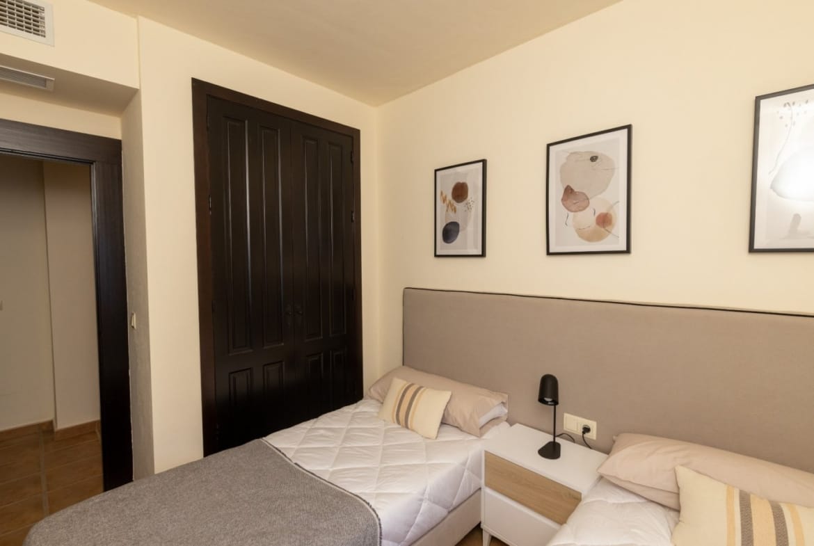 Twin beds beside dark fitted wardrobes and a doorway in Las Palas, Fuente Álamo, Murcia
