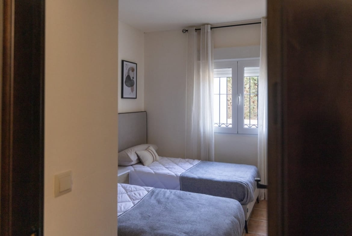 Twin bedroom viewed through a wooden doorway in Las Palas, Fuente Álamo, Murcia