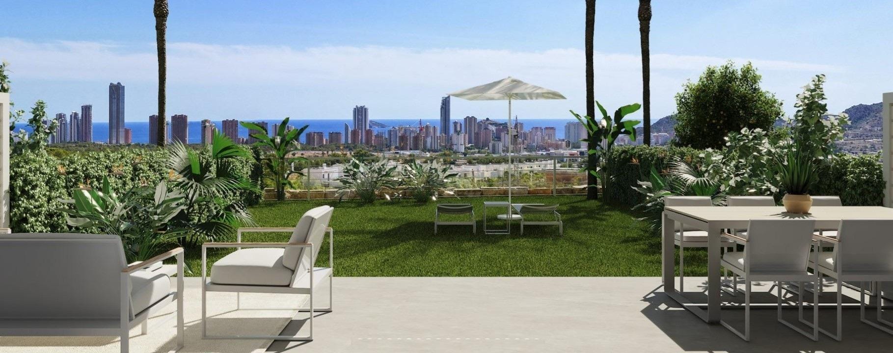 Garden terrace with dining furniture, palm trees and a distant coastal skyline in Sierra Cortina, Alicante
