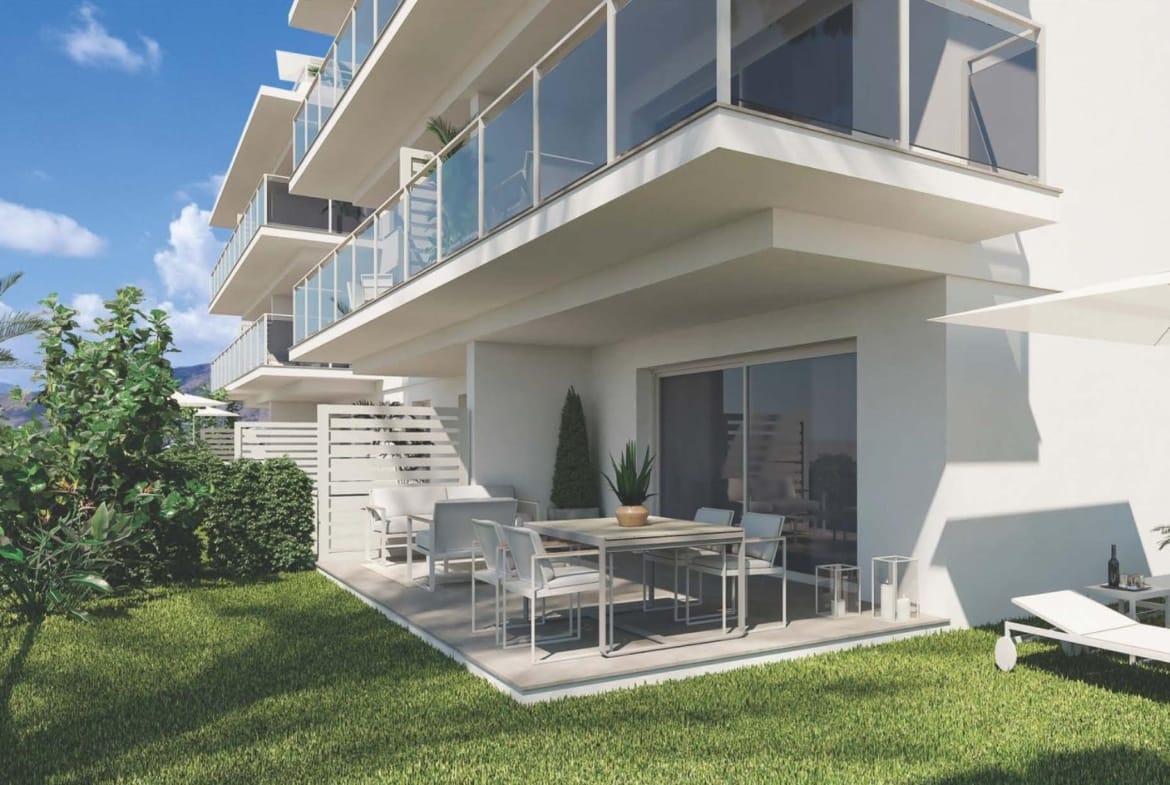 Apartment facade with glass balconies above a ground-floor patio and garden in Sierra Cortina, Alicante