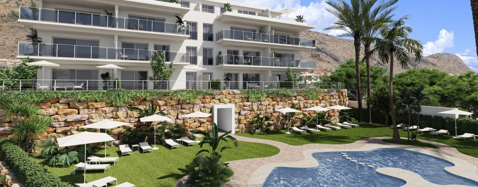 Apartment balconies above a communal swimming pool, lawn and landscaped stone terraces in Sierra Cortina, Alicante