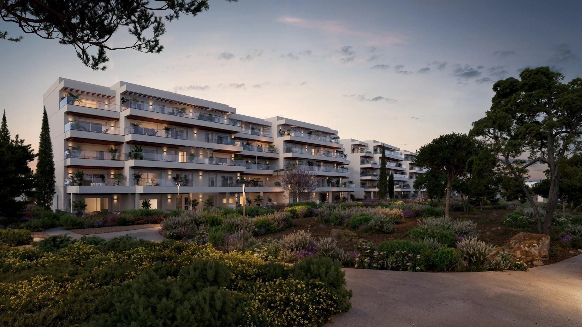 Modern apartment buildings at dusk surrounded by landscaped gardens in El Verger, Alicante