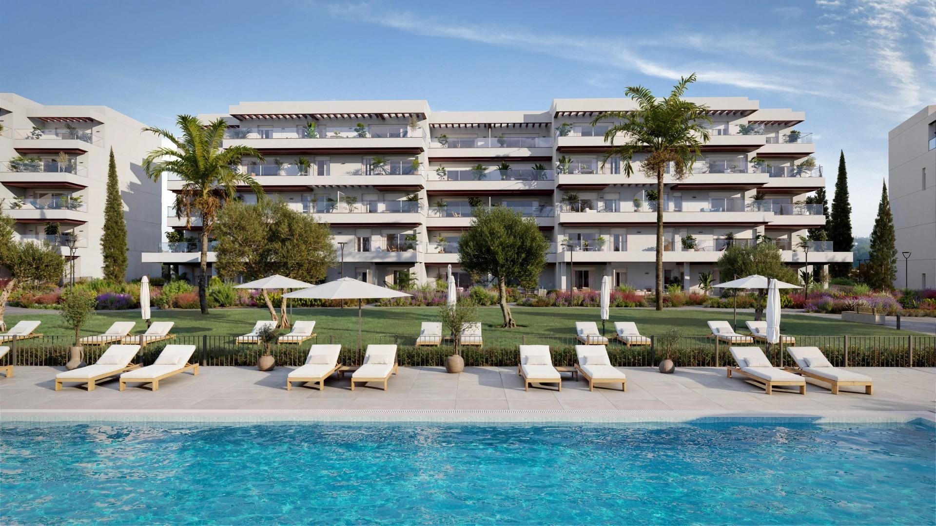 Communal swimming pool with sun loungers in front of the apartment buildings