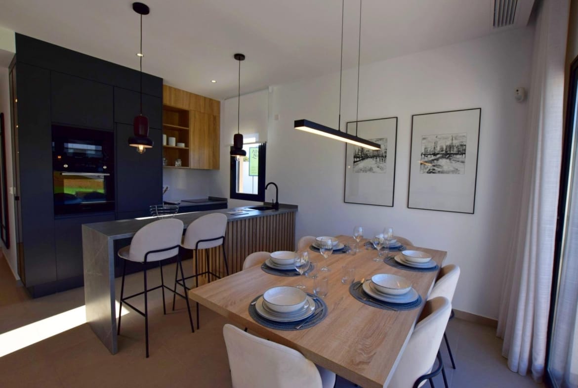 Dining area beside a modern kitchen with breakfast bar