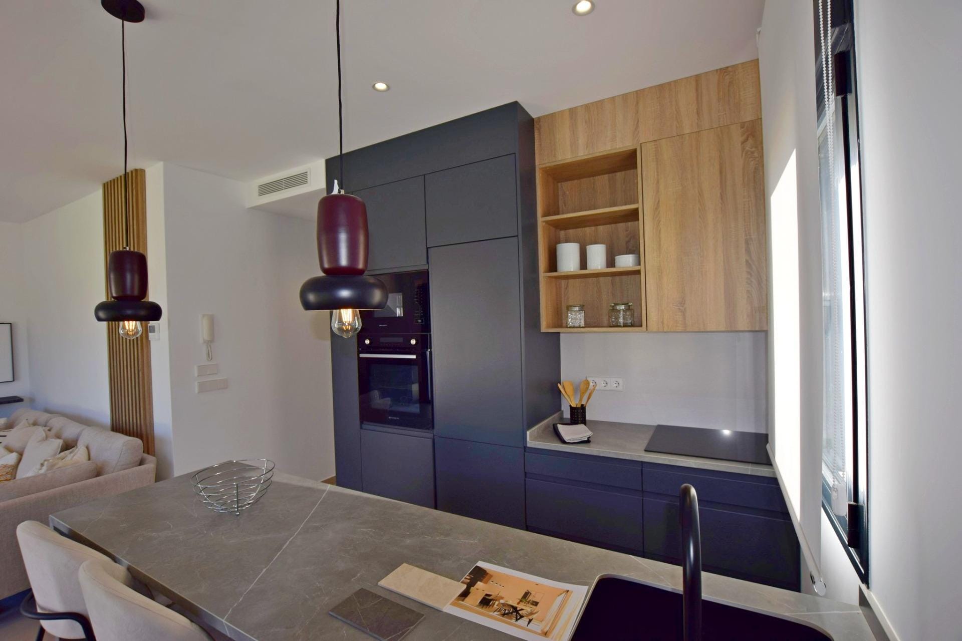 NEW-BUILD-APARTMENTS-IN-CONDADO-DE-ALHAMA-GOLF-COURSE-13 Modern fitted kitchen with dark cabinets and stone-look island