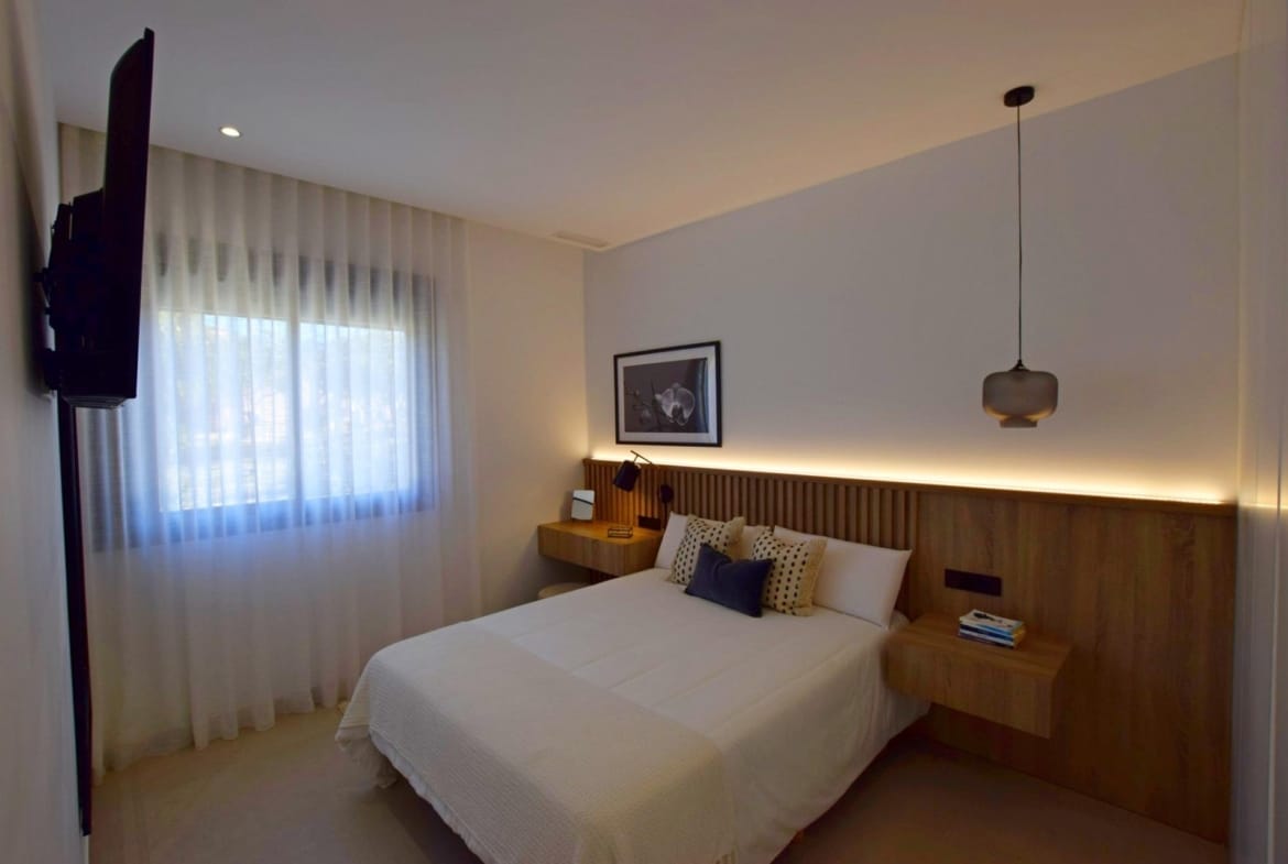 Main bedroom with wood headboard wall and soft lighting