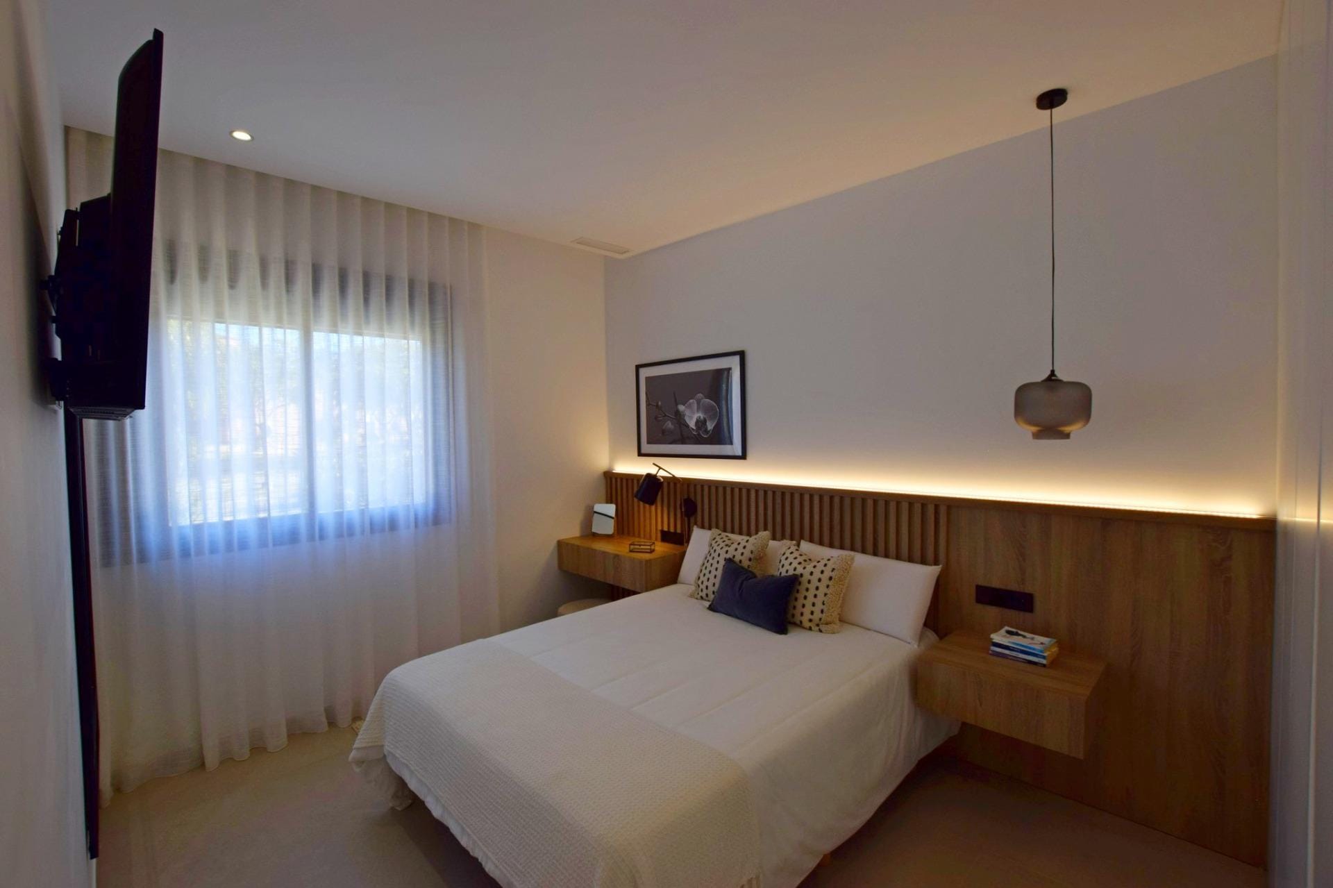 NEW-BUILD-APARTMENTS-IN-CONDADO-DE-ALHAMA-GOLF-COURSE-14 Main bedroom with wood headboard wall and soft lighting