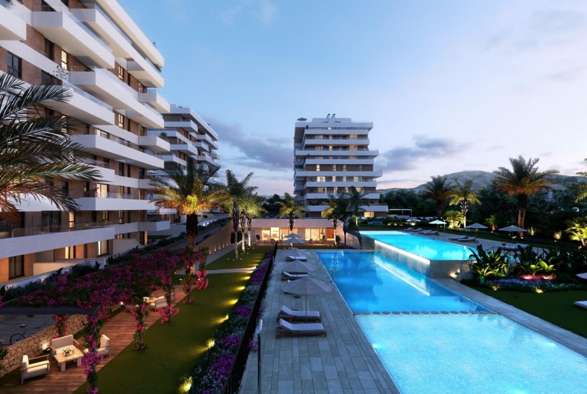 Illuminated communal pools and apartment buildings at dusk in Playa del Torres, Villajoyosa, Alicante