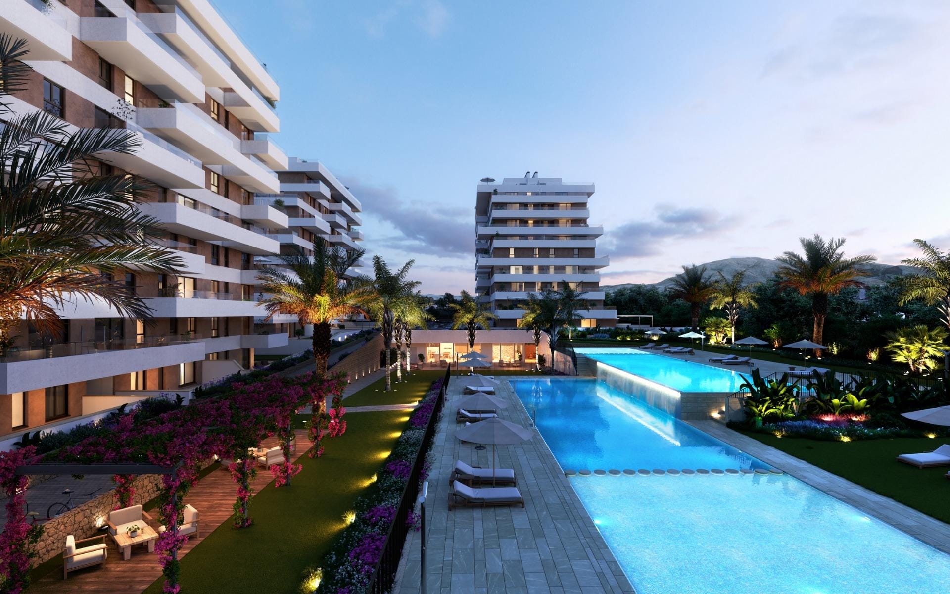 Illuminated communal pools and apartment buildings at dusk in Playa del Torres, Villajoyosa, Alicante