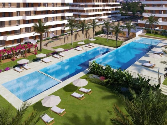 Communal pools with sun loungers and palm-lined lawns in Playa del Torres, Villajoyosa, Alicante