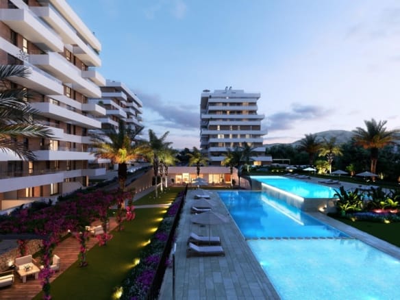 Illuminated communal pools and apartment buildings at dusk in Playa del Torres, Villajoyosa, Alicante