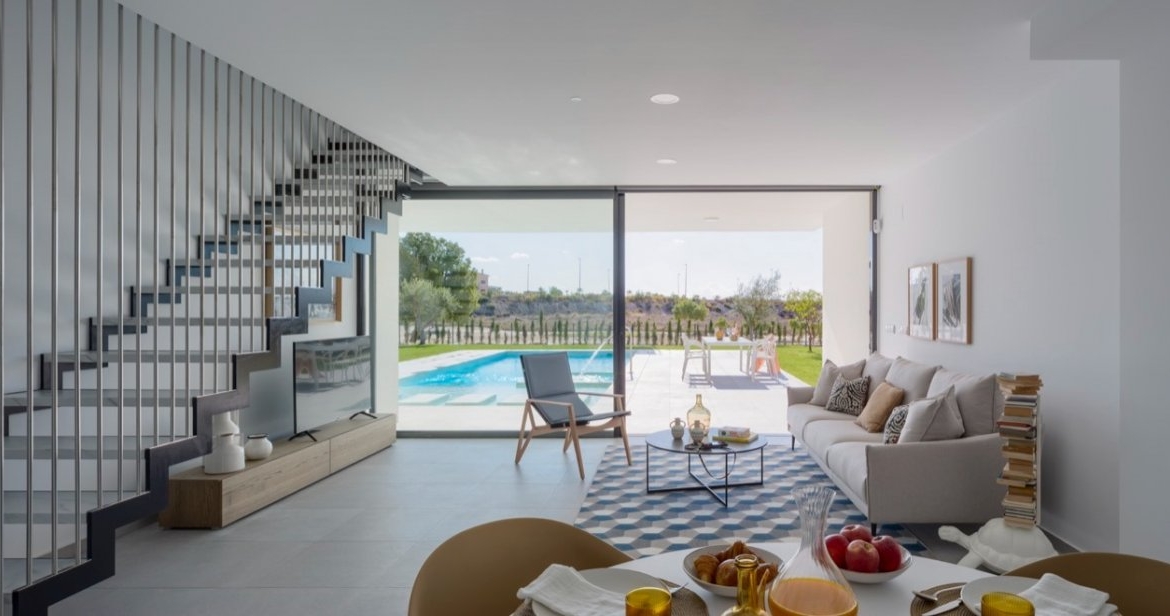 Open-plan living area with sofa, dining table and large sliding doors to pool