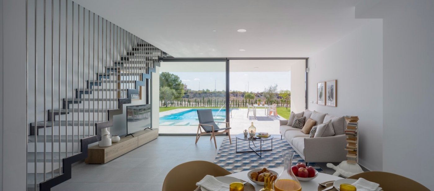 Open-plan living area with sofa, dining table and large sliding doors to pool
