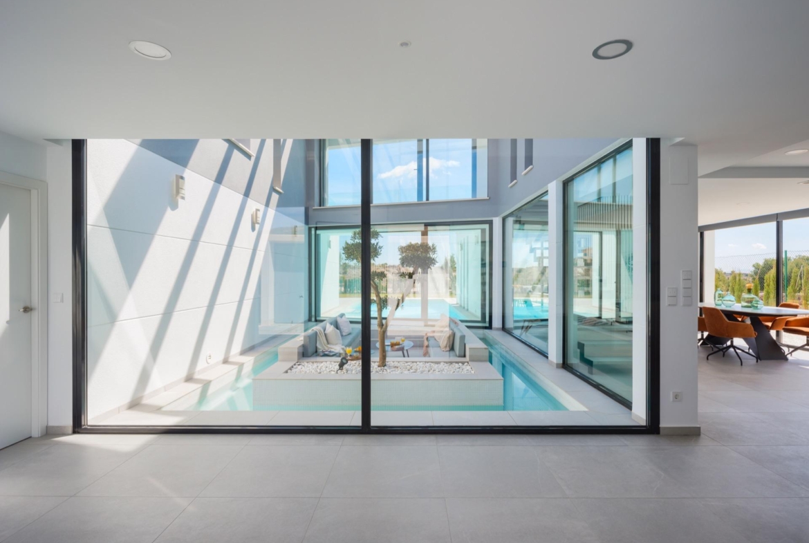 View through glass of a sunken seating area encircled by a narrow indoor water channel and planting