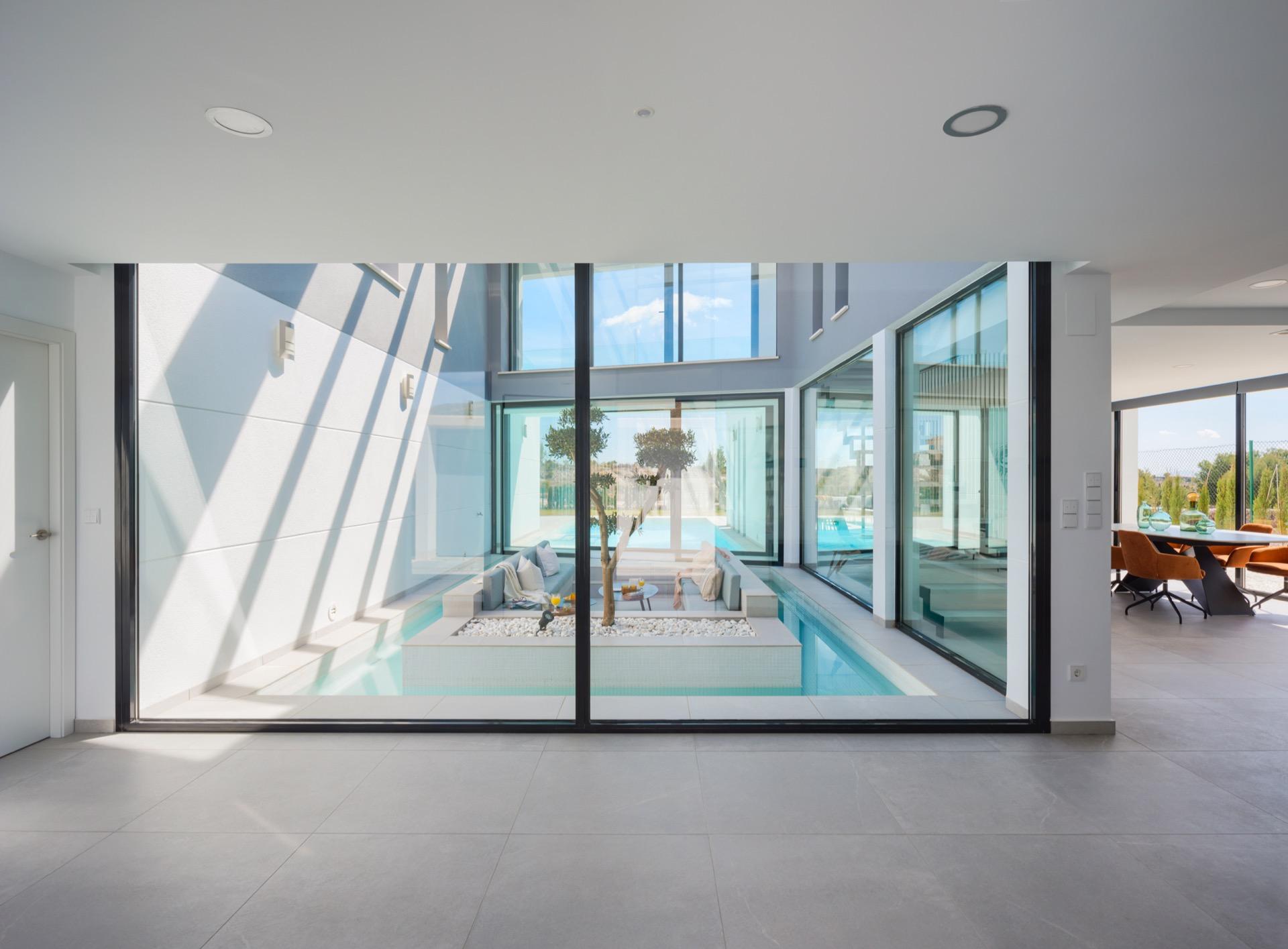 View through glass of a sunken seating area encircled by a narrow indoor water channel and planting