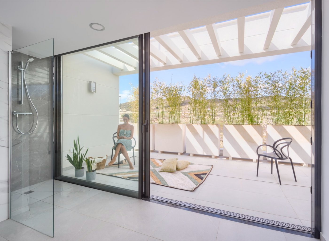 Covered balcony with glass balustrade, pergola shadows and view down to pool