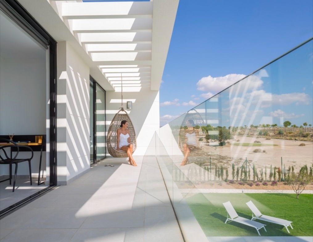 Long balcony with hanging chair, glass balustrade and pool visible below