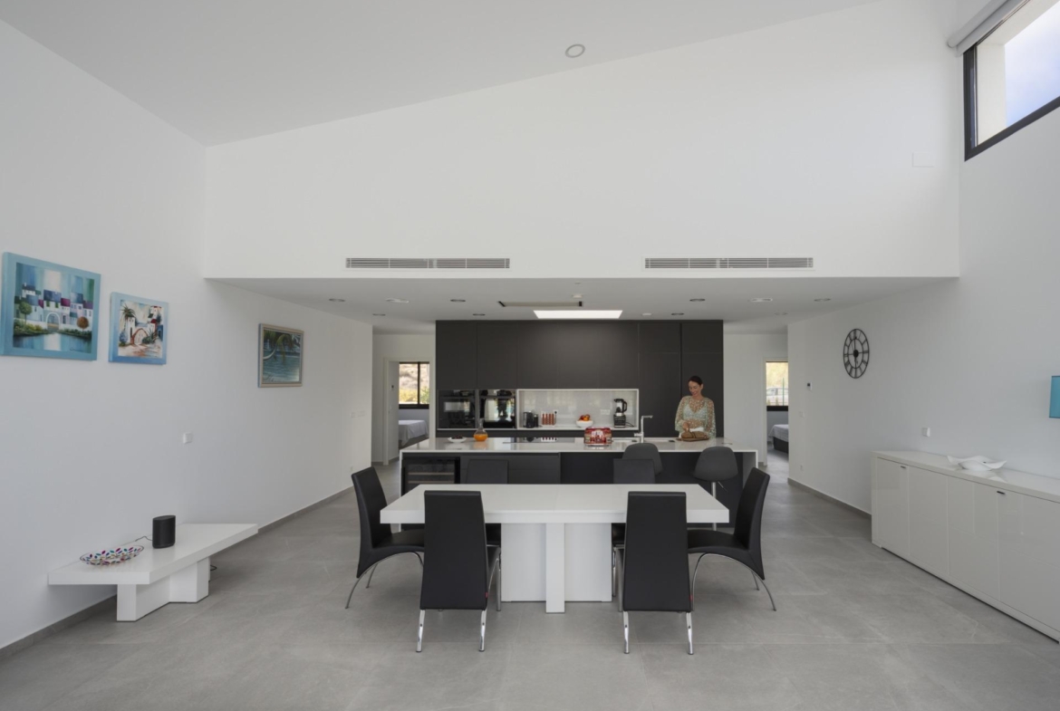 Open-plan kitchen and dining area with central island and vaulted white ceiling
