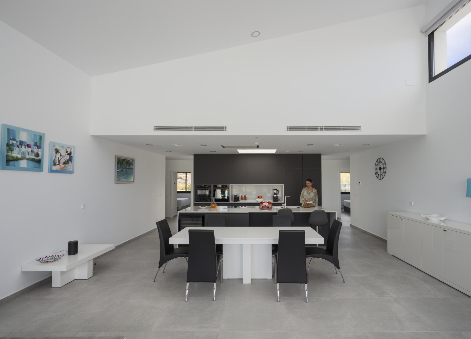 Open-plan kitchen and dining area with central island and vaulted white ceiling