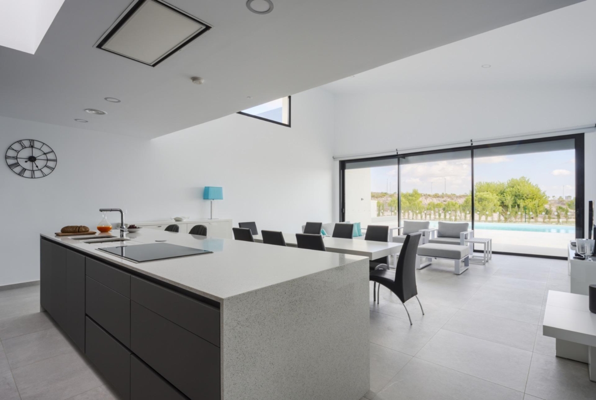 Dark kitchen island and breakfast bar facing large sliding doors with pool outside