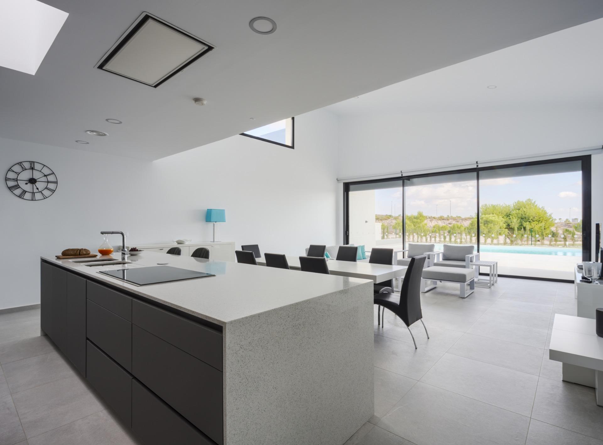 Dark kitchen island and breakfast bar facing large sliding doors with pool outside
