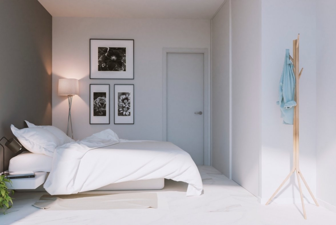 Bedroom with double bed, tripod floor lamp and three framed floral artworks on wall