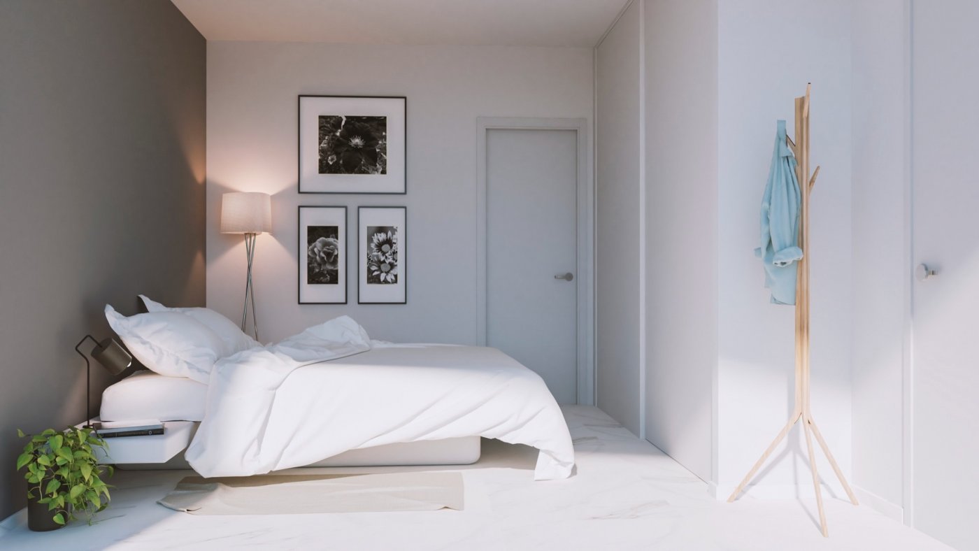 Bedroom with double bed, tripod floor lamp and three framed floral artworks on wall