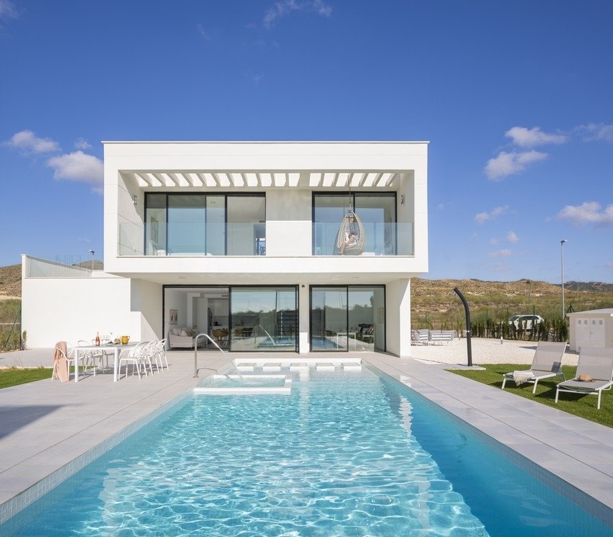 White two-storey villa facade with balcony overlooking a long swimming pool