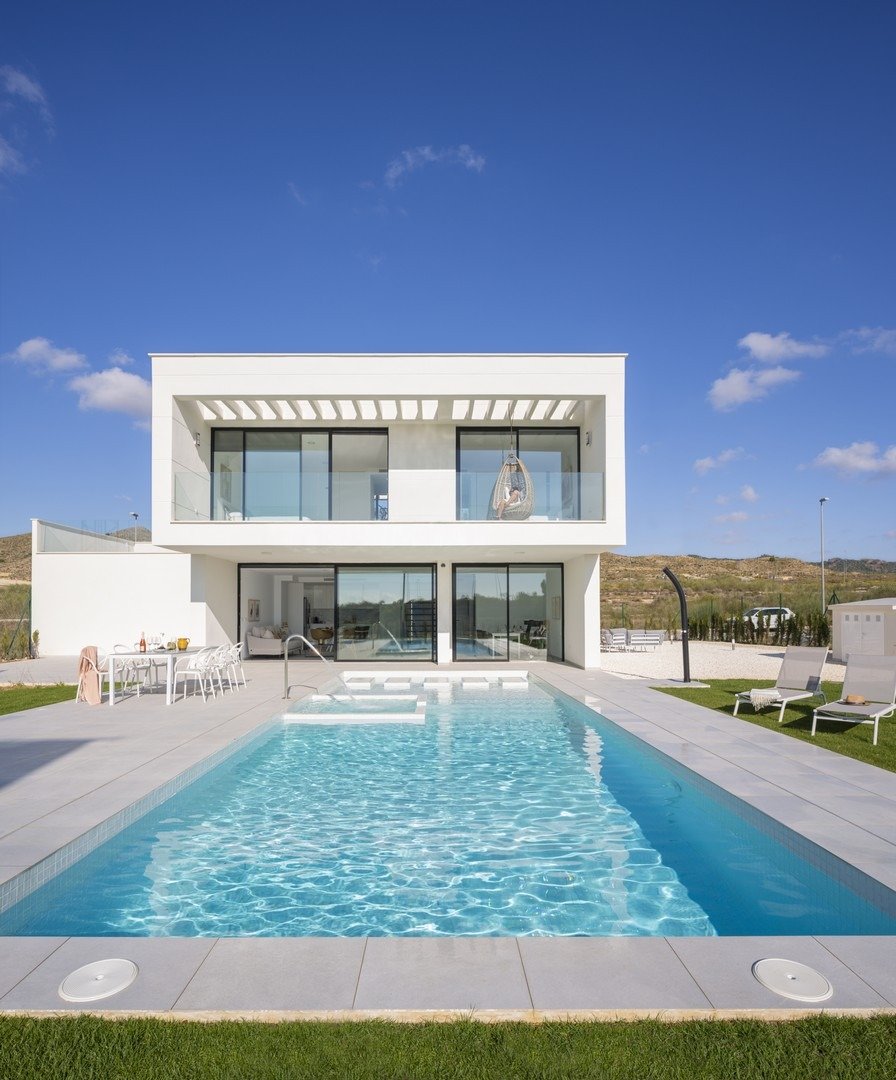 White two-storey villa facade with balcony overlooking a long swimming pool