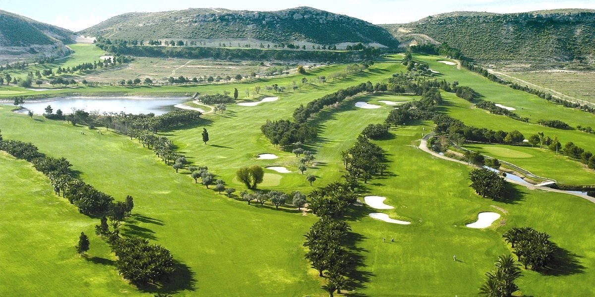 Aerial panorama of green fairways, water hazard and surrounding hills at a golf course