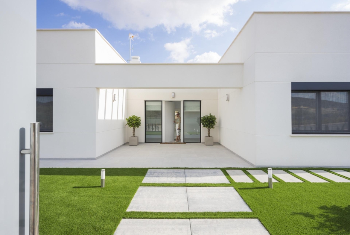 Covered entrance courtyard with glass doors, potted trees and person at the doorway