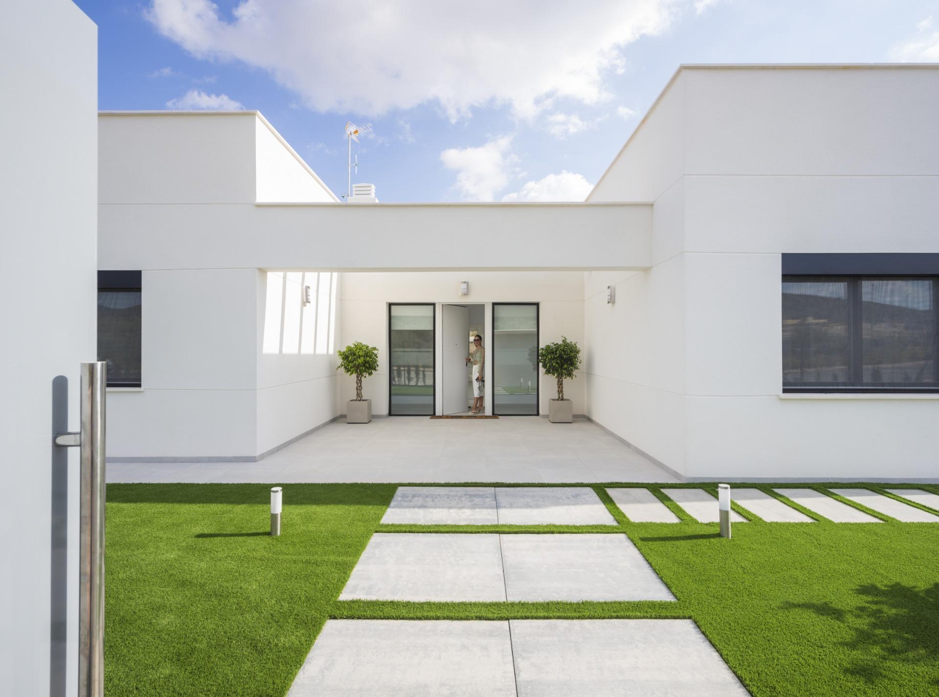 Covered entrance courtyard with glass doors, potted trees and person at the doorway